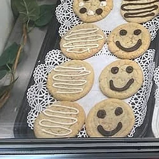 Trays of cookies in the case — chocolate chip, M&M, and smiley faces